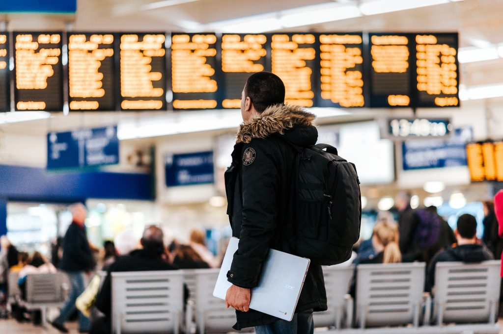 Homme de dos qui regarde les horaires de vols dans un aéroport